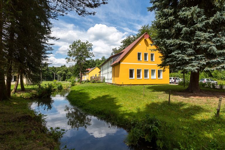 Das Wohnhaus der WG 2 und 3 im Jugenhilfezentrum Wolfersdorf hat einen neuen gelben Anstrich. Direkt daneben verläuft ein kleiner idyllischer Bach