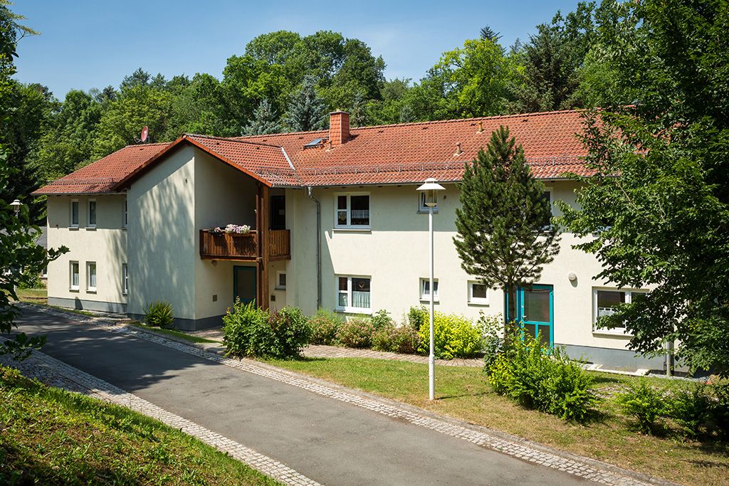 Eines der Wohnhäuser im Jugendhilfezentrum Bad Köstritz: ein modernes zweistöckiges Haus mit Holzbalkonen, umgeben vom satten Grün der Natur.