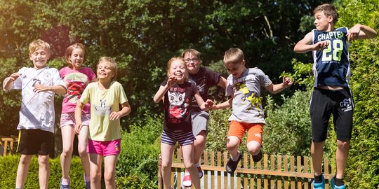Im Kinderhaus „Am Wald” in St. Gangloff geht es sehr fröhlich zu. Sieben Kinder hüpfen im Garten auf dem Trampolin.