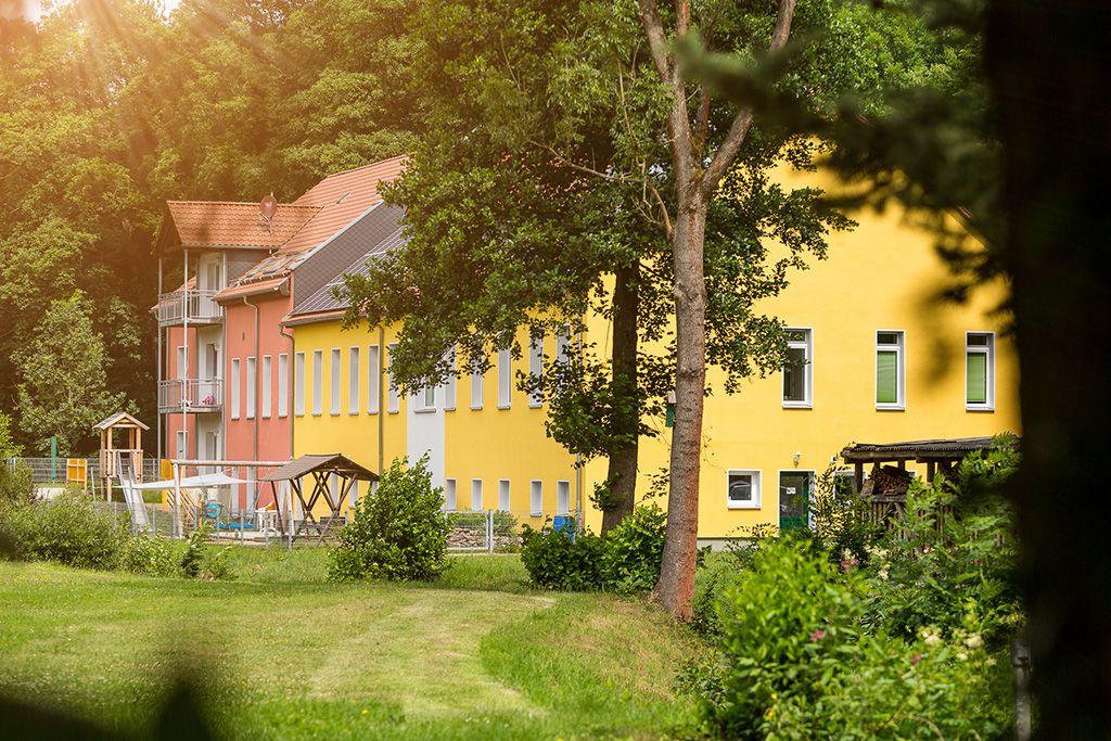 Blick durch die Bäume auf das Suchthilfezentrum für Mutter und Kind in Wolfersdorf.