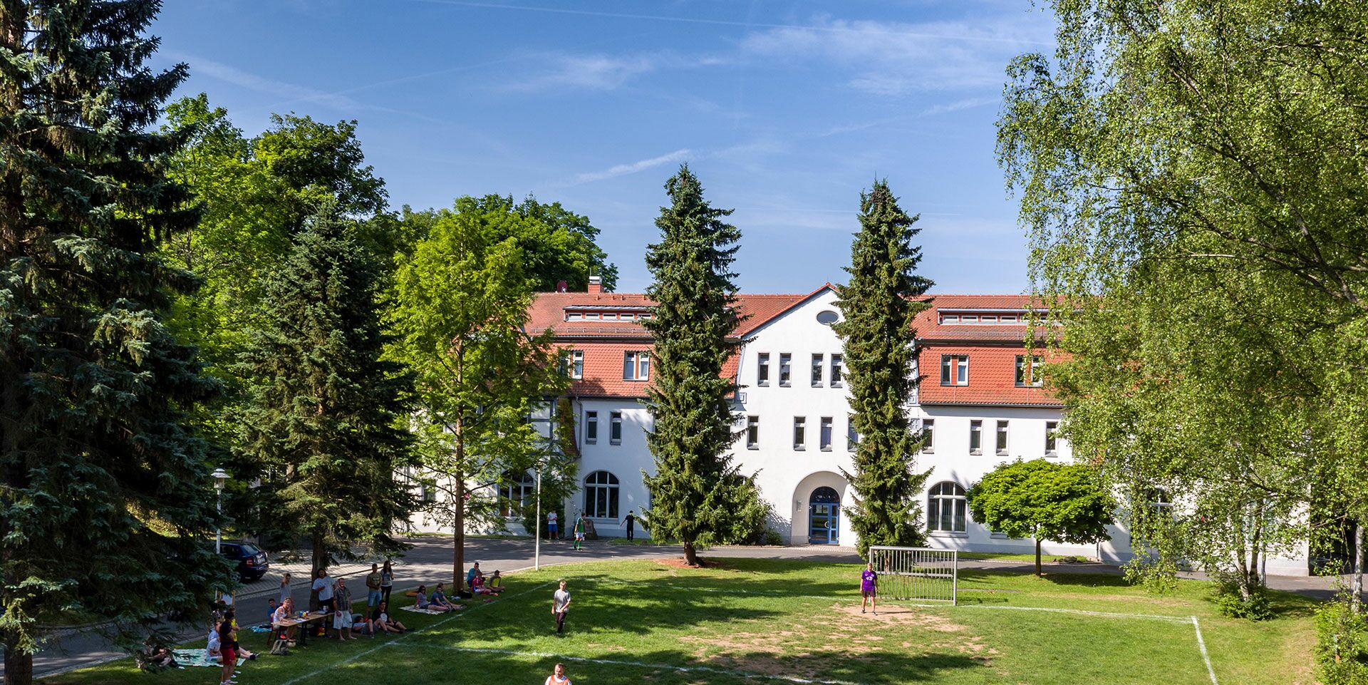 Blick auf das von der Sonne beschiene Förderschulzentrum Bad Köstritz. Direkt davor befindet sich ein Fußballplatz.